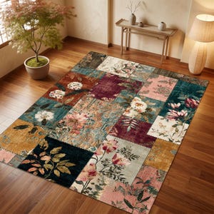 Könnte beinhalten: Ein rechteckiger Teppich mit einem Patchwork-Design aus verschiedenen Blumenmustern in den Farben Dunkelburgunder, Senfgelb, Blaugrün, Zartrosa und Creme. Der Teppich zeigt deutliche quadratische und rechteckige Abschnitte mit botanischen Motiven.