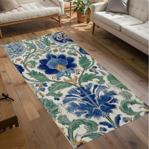 May include: Rectangular area rug with a floral pattern. The rug features large blue flowers with yellow centers, surrounded by green leaves and vines against a cream background. The design is symmetrical and detailed, with a vintage aesthetic.