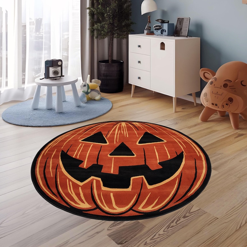 以下が含まれることがあります： ジャック・オ・ランタンの顔が描かれた、オレンジと黒の丸いハロウィン用ラグ