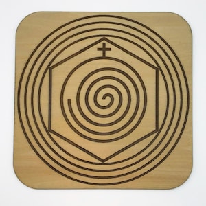 May include: A wooden coaster with a spiral design inside a hexagon shape. The hexagon has a cross at the top. The spiral is surrounded by concentric circles.