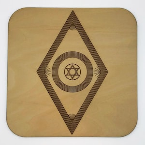 May include: A wooden coaster with a geometric design featuring a star of David inside a circle surrounded by concentric circles and a diamond shape.