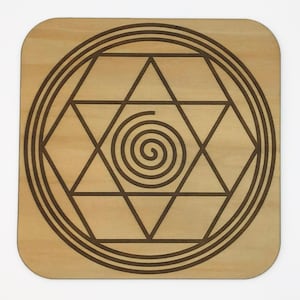 May include: A wooden coaster with a geometric design featuring a spiral in the center. The design is engraved into the wood and has a light brown color.