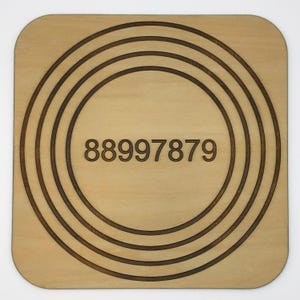 May include: A wooden coaster with concentric circles and the number 88997879 in the center.