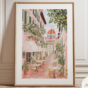 May include: A framed art print depicting a charming Italian street scene. The artwork features pink buildings with green shutters, outdoor cafes, and a distant cathedral. Lemon trees and floral arrangements add vibrant color to the scene.