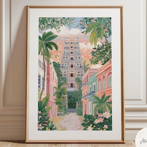 Op de afbeelding: Een ingelijste kunstdruk die een kleurrijke straatscène weergeeft met een hoge, sierlijke tempel aan het einde van de weg. Palmbomen en pastelkleurige gebouwen flankeren de straat, tegen een zachte zonsonderganghemel. Het kunstwerk zit in een gouden lijst.