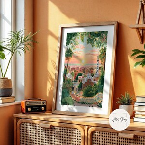 Pode incluir: Uma impress&atilde;o art&iacute;stica emoldurada com uma vibrante paisagem urbana com palmeiras, edif&iacute;cios e um caminho de mosaicos sinuoso. A obra de arte &eacute; exibida em um arm&aacute;rio de madeira com um r&aacute;dio vintage e uma planta em vaso. A paleta de cores inclui laranjas, verdes e azuis quentes.