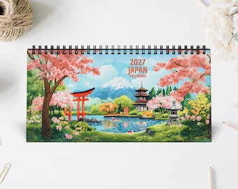 May include: A 2027 Japan calendar with a spiral binding featuring a colorful illustration of Mount Fuji, a red torii gate, a pagoda, and cherry blossom trees surrounding a pond with koi fish. The text 2027 JAPAN CALENDAR is printed in orange.