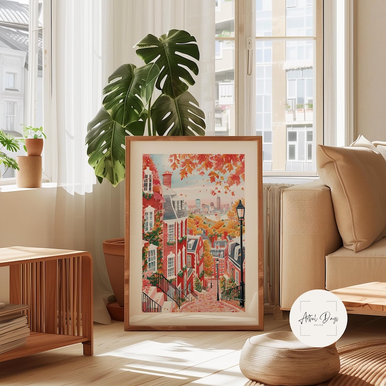 May include: A framed watercolor print depicts a vibrant autumn scene of a city street lined with red brick buildings and trees with orange and red leaves. The artwork is displayed in a living room setting with a neutral color palette.