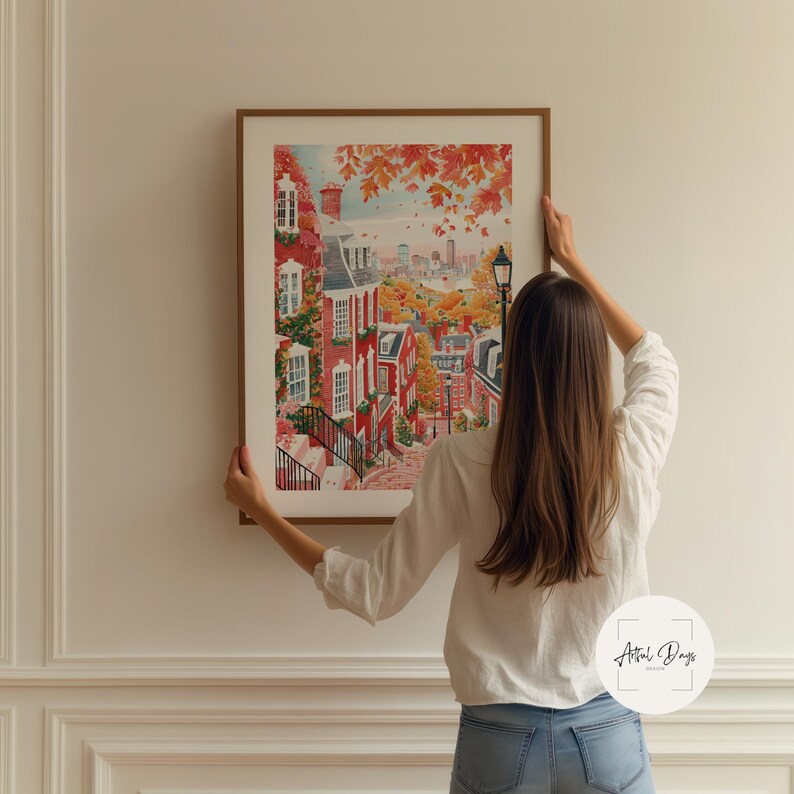 May include: A framed watercolor print depicts a vibrant autumn scene of a city street with red brick buildings, trees with orange leaves, and a distant cityscape. The artwork is in a brown wooden frame.
