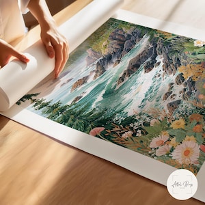 May include: A person unrolling a large art print featuring a watercolor landscape of a waterfall cascading down rocky cliffs. The print showcases vibrant greens, blues, and floral accents, with a white border. The print is on a wooden surface.