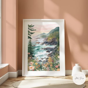 May include: A framed watercolor print of a coastal landscape. The artwork depicts a rocky shoreline with crashing waves, lush green trees, and colorful wildflowers. The sky is a soft pink and the overall scene is serene.