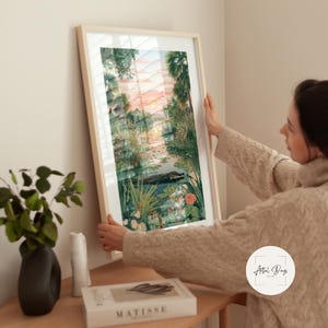 Puede incluir: Una impresi&oacute;n art&iacute;stica enmarcada que presenta un paisaje sereno con un cuerpo de agua, vegetaci&oacute;n exuberante y un cielo al atardecer. La obra de arte incluye un caim&aacute;n en el agua. El marco es de color claro.
