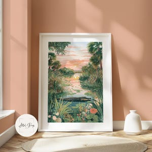 Puede incluir: Una impresi&oacute;n art&iacute;stica enmarcada que representa una serena escena de pantano. La obra de arte presenta una puesta de sol sobre una tranquila masa de agua, con un caim&aacute;n visible. La exuberante vegetaci&oacute;n y las flores rodean el agua, creando un paisaje vibrante y naturalista. La impresi&oacute;n est&aacute; enmarcada en blanco.
