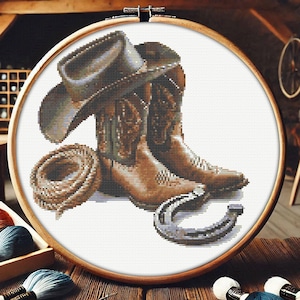 May include: A brown cowboy hat, a pair of brown leather cowboy boots, and a horseshoe on a white background. The boots have intricate stitching and designs.