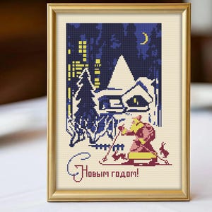 May include: Cross-stitch artwork in a gold frame depicts a winter scene with a skier, a house, and a cityscape under a crescent moon. The text "С Новым годом!" is stitched in cursive. The color palette includes shades of blue, yellow, and red.