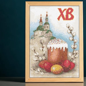 May include: A cross-stitch embroidery design featuring a traditional Russian Easter cake with white icing and sprinkles, surrounded by Easter eggs and pussy willow branches. The background depicts a church with golden domes and the Cyrillic letters "XB" for "Christ is Risen".
