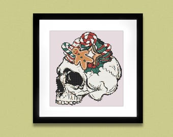 May include: Cross-stitch art of a skull decorated with Christmas candy and a gingerbread man. The skull is white with black shading, and the candy includes red and white striped candy canes, green holly, and a gingerbread man.