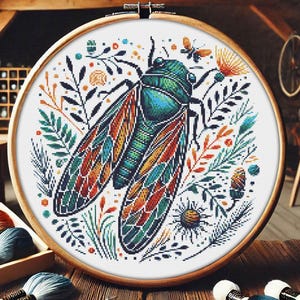 May include: A cross-stitch embroidery design featuring a colorful cicada with intricate details, surrounded by stylized floral elements in shades of green, orange, and blue.