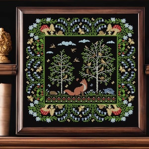 May include: Framed cross-stitch depicting a forest scene with a fox, birds, and trees. The artwork has a black background with a border of flowers, mushrooms, and butterflies. The frame is brown.