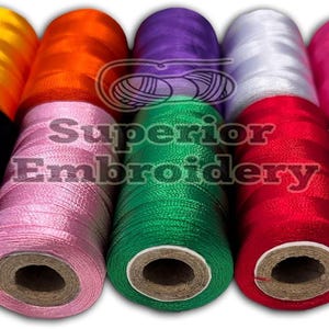 May include: Assortment of 10 spools of embroidery thread in various colours, including black, pink, green, red, blue, white, orange, yellow, and purple. The spools are arranged in a row and have a brown cardboard centre.