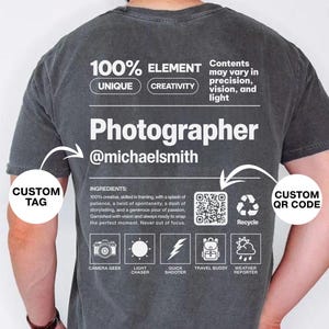 May include: Dark gray t-shirt with the word "Photographer" and the @michaelsmith username printed in white. The shirt also features text about creativity and photography-related icons. A custom QR code is also visible.