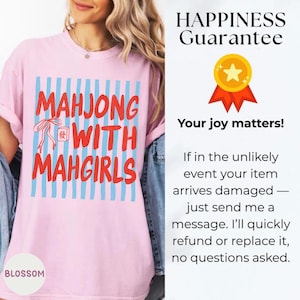 Peut inclure: Un t-shirt rose clair avec un motif &agrave; rayures verticales bleu clair et le texte rouge "MAHJONG WITH MAHGIRLS", accompagn&eacute; d'une petite illustration d'une tuile de mah-jong et d'un ruban rouge. Le t-shirt est port&eacute; avec une veste en jean bleu.