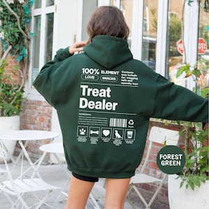 May include: Forest green hoodie with the text "Treat Dealer" and ingredient icons. The hoodie also has the text "100% ELEMENT LOVE SNACKS" and "Contents may include fur, wagging tails and squeaky toys."
