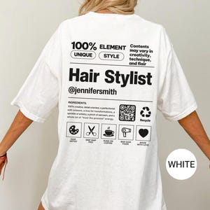 K&ouml;nnte beinhalten: Ein wei&szlig;es T-Shirt mit schwarzem Text und Grafiken auf der R&uuml;ckseite. Das Design &auml;hnelt einem Produktetikett mit dem Text 100% ELEMENT UNIQUE STYLE, Hair Stylist, @jennifersmith, und einer Zutatenliste mit Symbolen f&uuml;r Palette, Schere, Kaffee, Haartrockner und Herz.