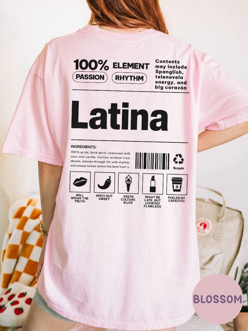 Może przedstawiać: Jasnor&oacute;żowa koszulka z napisem "Latina" dużymi czarnymi literami. Koszulka zawiera tekst i grafikę, w tym "100% Element" i ikony składnik&oacute;w. Na koszulce znajduje się r&oacute;wnież napis "Blossom".