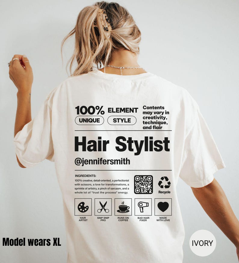 K&ouml;nnte beinhalten: Ein elfenbeinfarbenes T-Shirt mit einer schwarzen Grafik auf der R&uuml;ckseite, die einem Produktetikett &auml;hnelt. Es enth&auml;lt den Text Hair Stylist, @jennifersmith, eine Zutatenliste, einen QR-Code sowie Symbole f&uuml;r Palette, Schere, Kaffee, F&ouml;hn und Herz.