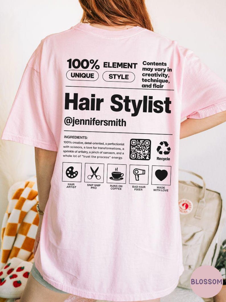 K&ouml;nnte beinhalten: Ein hellrosa T-Shirt mit schwarzem Text und Grafiken auf der R&uuml;ckseite. Das Design imitiert ein Produktetikett mit dem Text Hair Stylist, @jennifersmith, und einer Liste von Inhaltsstoffen wie kreativ, detailorientiert und Liebe zur Ver&auml;nderung.