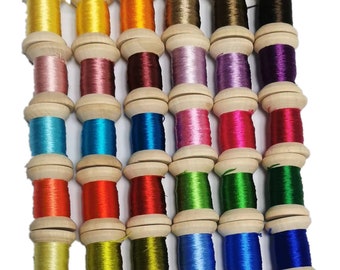 Könnte beinhalten: Eine Sammlung farbenfroher Stickgarnspulen. Die Spulen sind aus Holz und mit lebendigen Fäden in Gelb-, Rosa-, Blau-, Rot-, Grün- und Lilatönen gefüllt. Die Fäden sind eng gewickelt und bilden eine ordentliche und übersichtliche Darstellung.