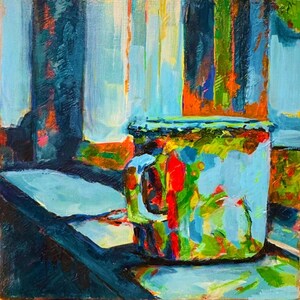 May include: A blue and green mug with a handle sits on a dark blue surface. The mug is painted with abstract brushstrokes in shades of blue, green, red, and yellow.
