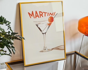 May include: A framed print of a Martini advertisement with the word "MARTINI" in red letters and a martini glass with a cherry on a stick. The print is in a gold frame and is sitting on a glass table.