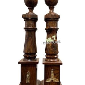 Puede incluir: Un par de pilares decorativos de madera con detalles dorados. Cada pilar tiene una parte superior redonda y una base cuadrada. Los pilares están hechos de madera oscura y tienen un acabado pulido.