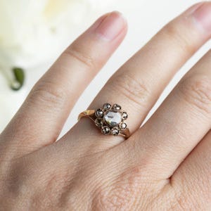 May include: A gold ring with a large, clear, faceted gemstone surrounded by a halo of smaller, faceted gemstones.