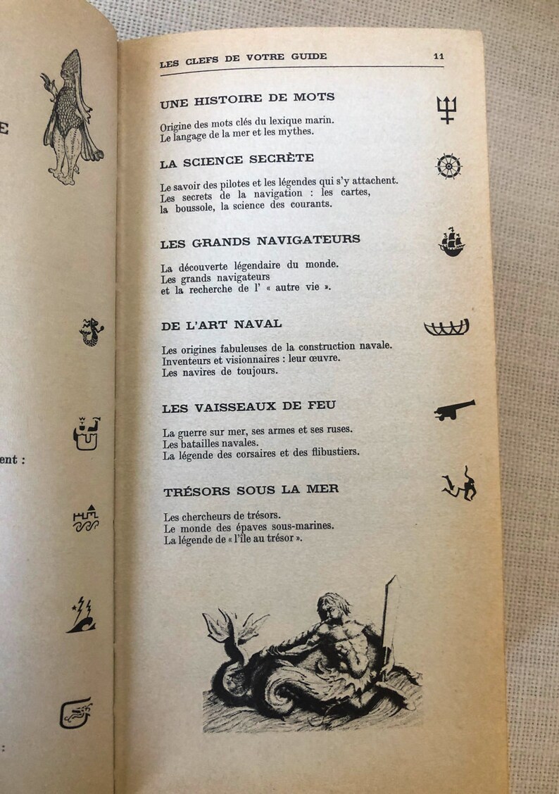 K&ouml;nnte beinhalten: Offene Buchseite mit franz&ouml;sischem Text und Illustrationen. Der Titel "LES CLEFS DE VOTRE GUIDE" steht oben. Zu den Abschnitten geh&ouml;ren "UNE HISTOIRE DE MOTS" und "LA SCIENCE SECR&Egrave;TE". Illustrationen eines Dreizacks, eines Steuerrads und eines Schiffs sind sichtbar.