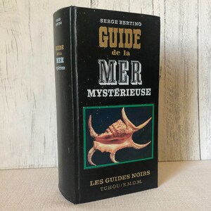 K&ouml;nnte beinhalten: Ein schwarzes Hardcover-Buch mit dem Titel "GUIDE de la MER MYSTERIEUSE" von Serge Bertino. Das Cover hat goldene und wei&szlig;e Schrift und eine Muschelabbildung. Das Buch geh&ouml;rt zur Reihe "LES GUIDES NOIRS".
