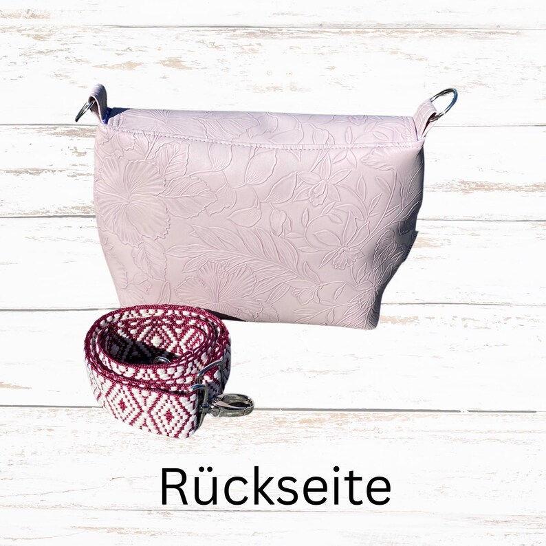 May include: A pale pink handbag with a floral embossed pattern, and a patterned strap. The strap is white and burgundy with a geometric design. The word "R&uuml;ckseite" is printed at the bottom of the image.
