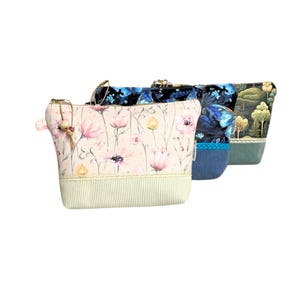 May include: Three zippered pouches with different floral and patterned designs. The pouch on the left has a pink floral pattern, the middle pouch has a blue and black butterfly pattern, and the pouch on the right has a green and brown forest pattern.