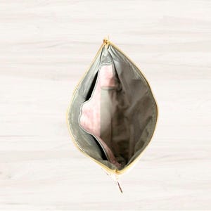May include: An open zippered pouch with a gray exterior and a pink interior. The pouch is made of a soft, textured fabric.
