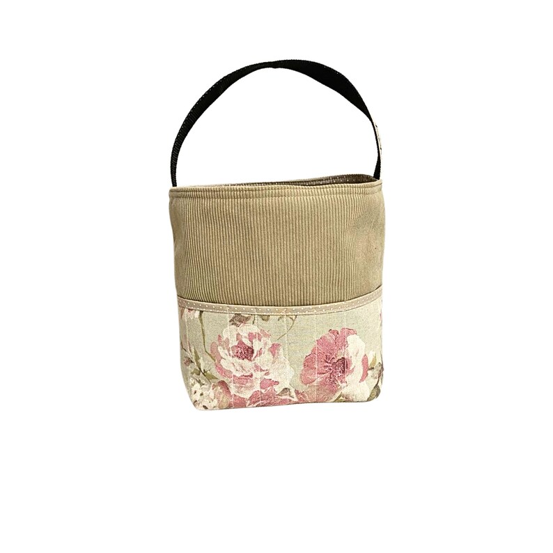 Puede incluir: Una peque&ntilde;a bolsa de tela beige con un asa negra. La bolsa tiene un estampado floral con rosas rosas en la mitad inferior.