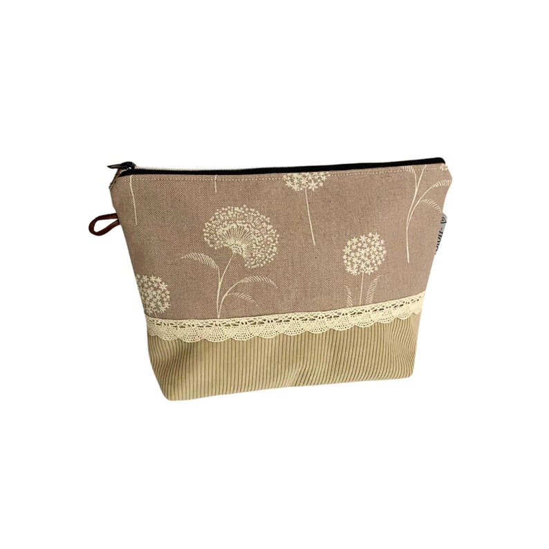 May include: A brown zippered pouch with a floral pattern and a beige lace trim. The pouch is made of a soft, textured fabric.