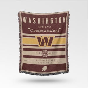 May include: A burgundy, tan, and gold woven throw blanket with the text "WASHINGTON Commanders" and a large "W" logo. The blanket includes the text "EST. 1932" and a football graphic. The fringe is black.