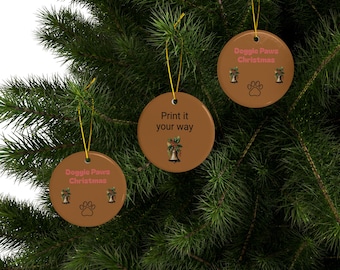 May include: Three round, brown Christmas ornaments hanging on a green Christmas tree. The ornaments have gold strings and feature the text "Doggie Paws Christmas", paw prints, and bell graphics. One ornament says "Print it your way".