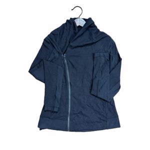 May include: A black zip-up jacket with an unusual asymmetrical cut, displayed on a hanger. The jacket features long sleeves and a draped collar. The text "RETRO REVERIE" is at the top, and "WE GIVE CLOTHES A SECOND CHANCE" at the bottom.
