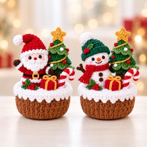 May include: Two crocheted Christmas decorations featuring a Santa Claus and a snowman, each sitting in a brown basket base with white trim. Both figures are accompanied by a green Christmas tree with a yellow star, a red gift, and a candy cane.