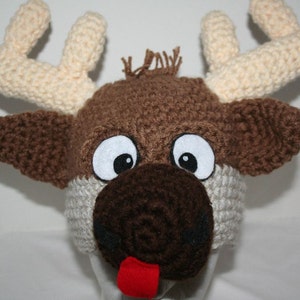 May include: A crocheted reindeer hat with brown and white yarn, large white eyes, a brown nose, and a red tongue.