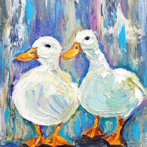 An oil painting depicts two white ducks with orange beaks and feet. The ducks are positioned against a background of blue, purple, and white brushstrokes. The artwork has a textured, impasto style, with visible brushstrokes.