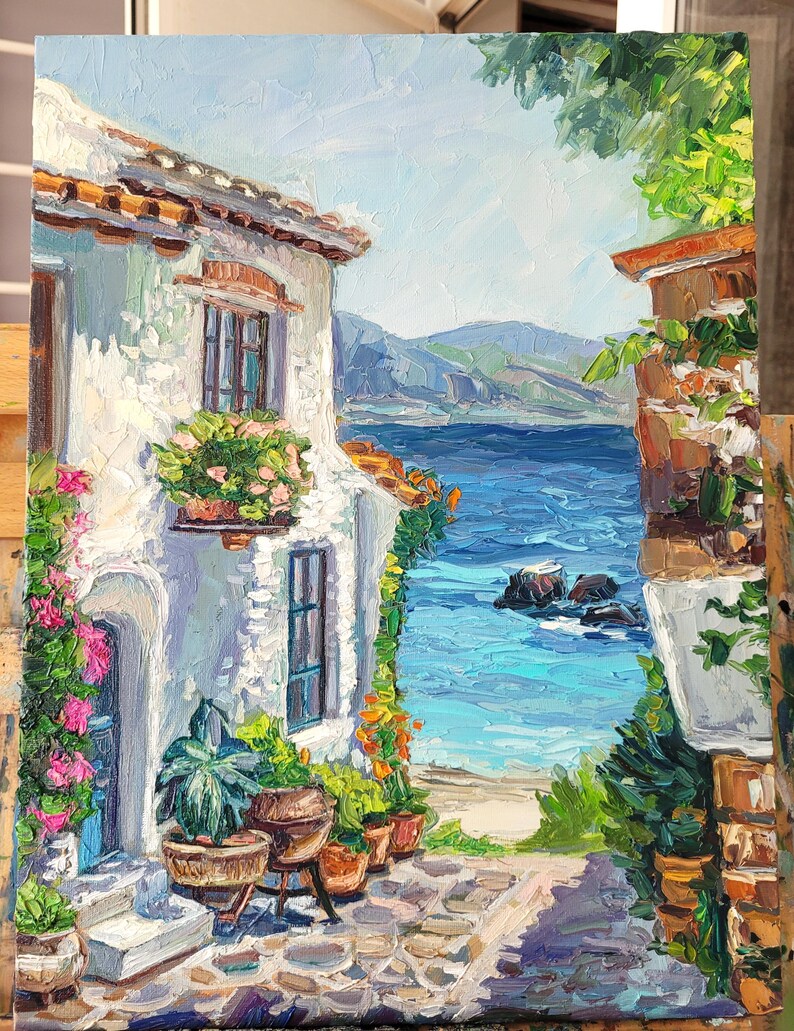 May include: An oil painting on canvas depicting a Mediterranean coastal scene with a white stucco building, vibrant pink flowers, green potted plants, and a stone patio overlooking a deep blue sea with distant mountains under a bright sky.